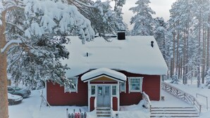 Eine rote Holzhütte mit schneebedecktem Dach und Stufen zum Eingang.