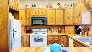 Una cocina con armarios de madera, un refrigerador, un microondas, una estufa y un lavamanos.