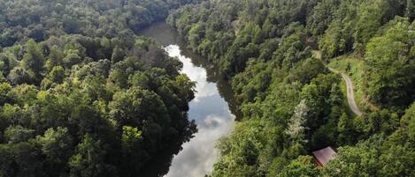 Vista aérea de un área boscosa con un río, una carretera sinuosa y un edificio pequeño.