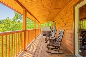 Una terraza de madera con sillas mecedoras y un jacuzzi.