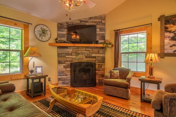 Una sala de estar acogedora con chimenea de piedra, televisor de pantalla plana y asientos cómodos.