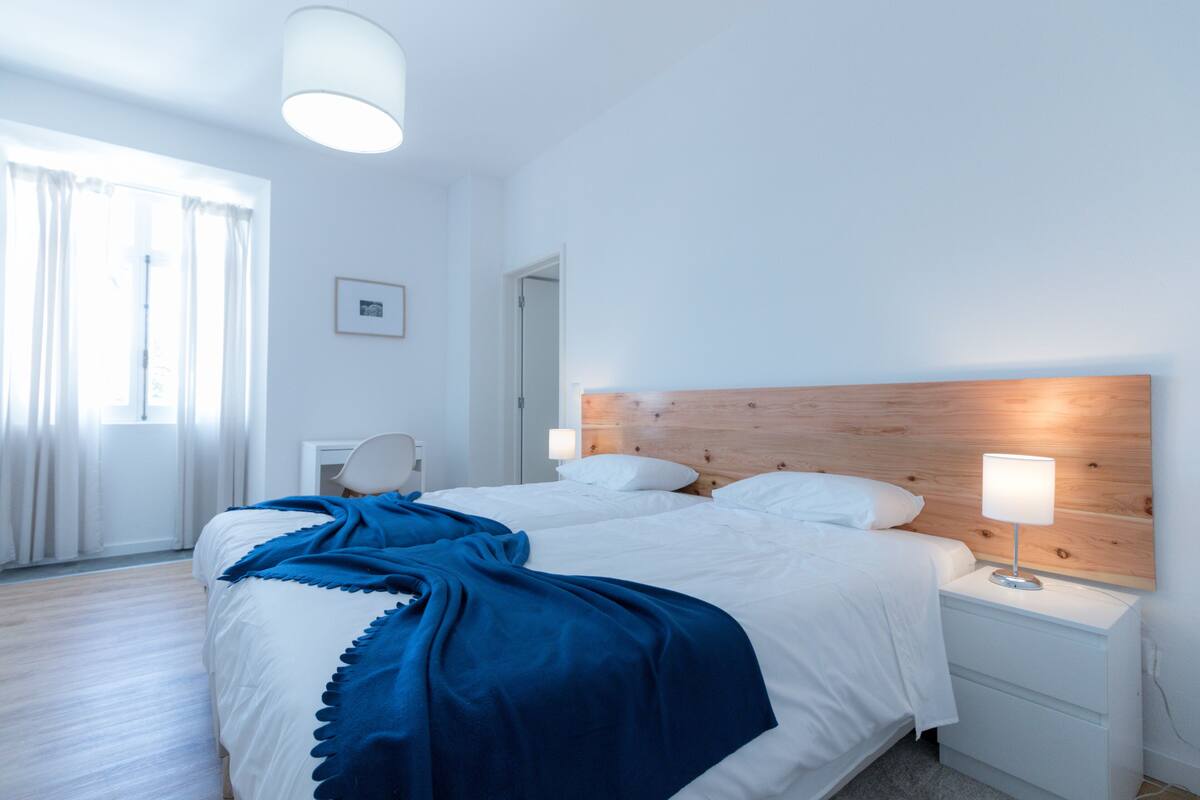 Un dormitorio con una cama grande, una mesita de noche con lámpara y un cabecero de madera.