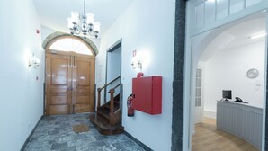 Un pasillo con una puerta de madera, un extintor y un mostrador de recepción.