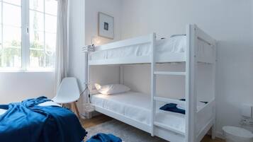 Une chambre avec un lit superposé, un bureau, une chaise et une fenêtre.