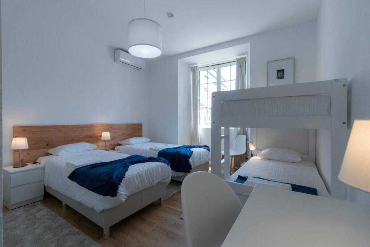 Una habitación de hotel moderna con dos camas, una litera, un escritorio y una silla.