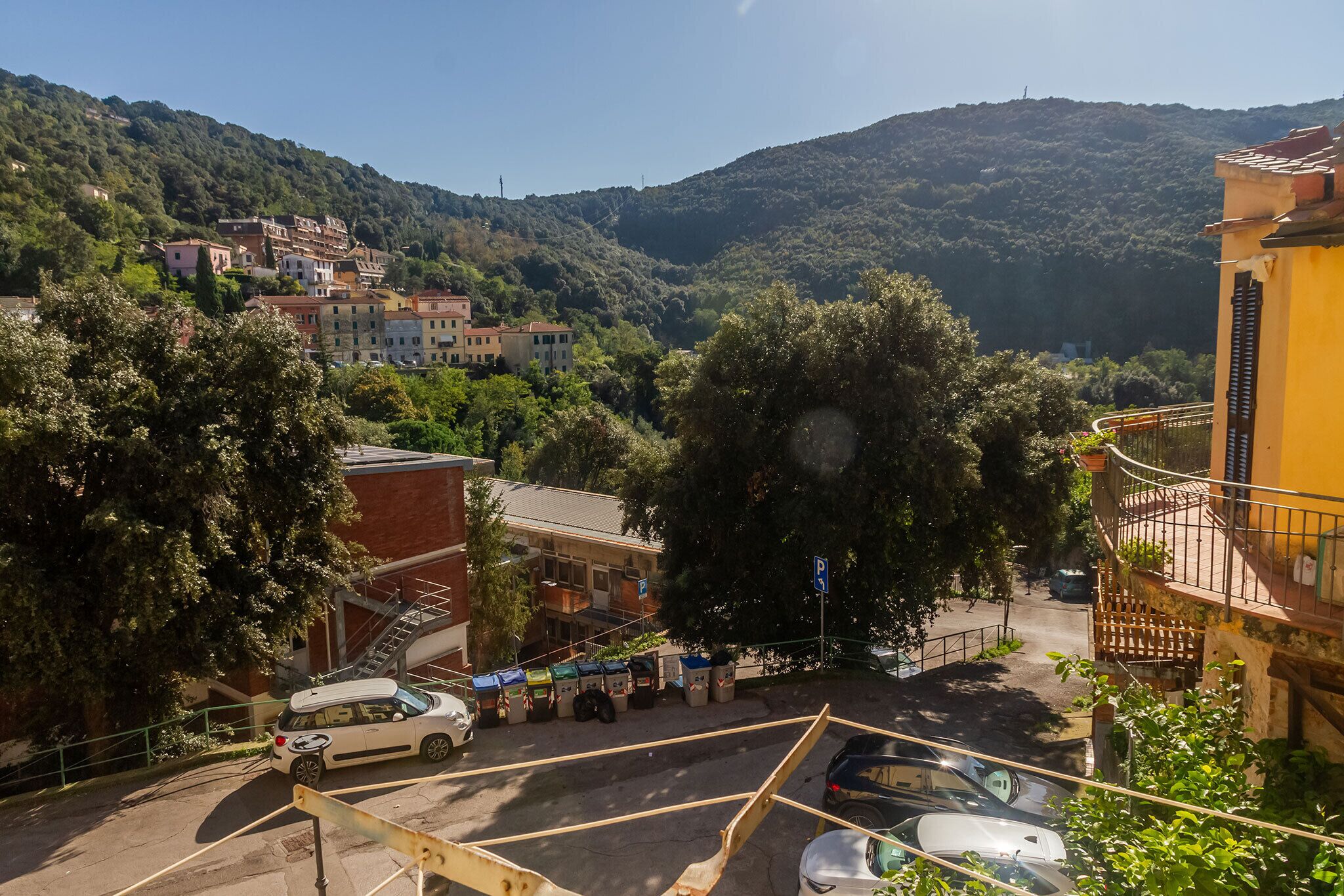 Zona residencial amb edificis, un aparcament i un turó.