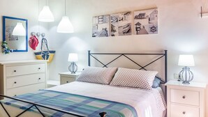 Un dormitorio ordenado con cama, mesitas de noche, un espejo y decoración en la pared.