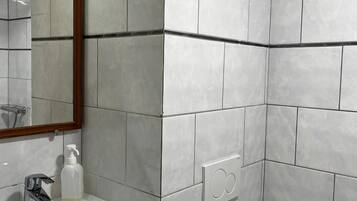 A bathroom with a white sink, a mirror with a wooden frame, and tiled walls.