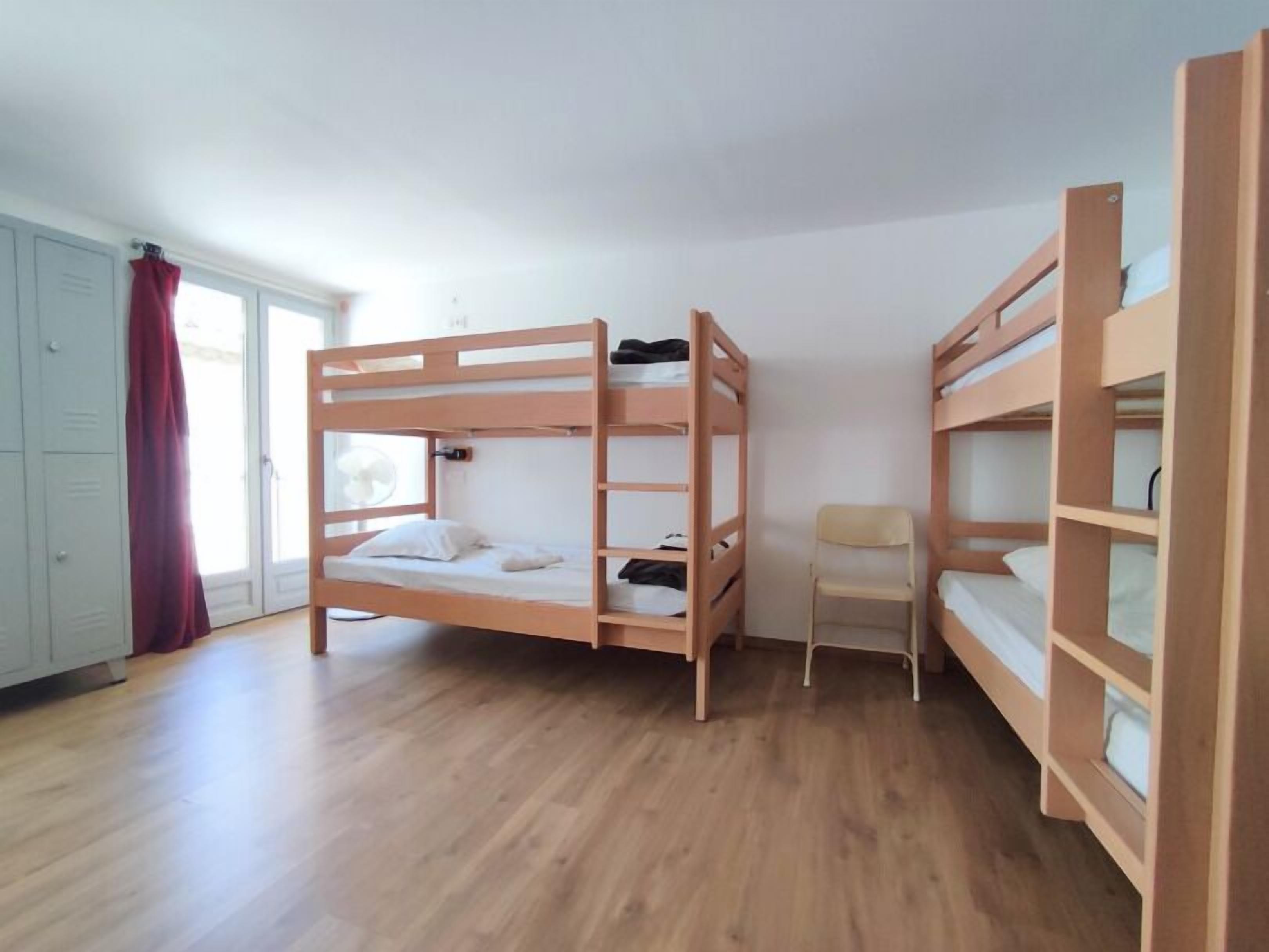 A room with two bunk beds, a chair, and a wardrobe.