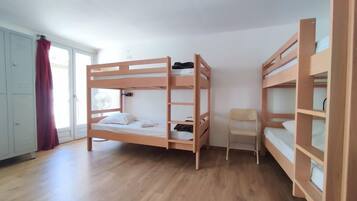 A room with two bunk beds, a chair, and a wardrobe.