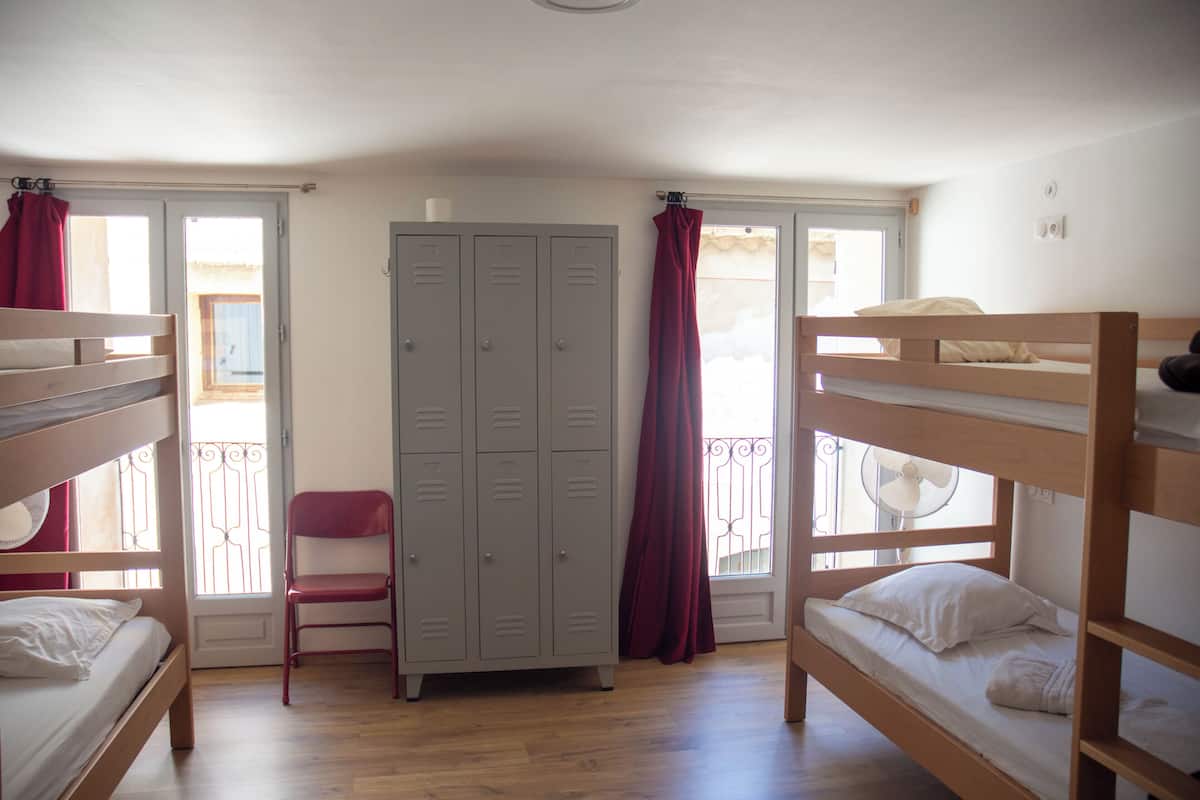 A dormitory room with bunk beds, a chair, and a wardrobe.