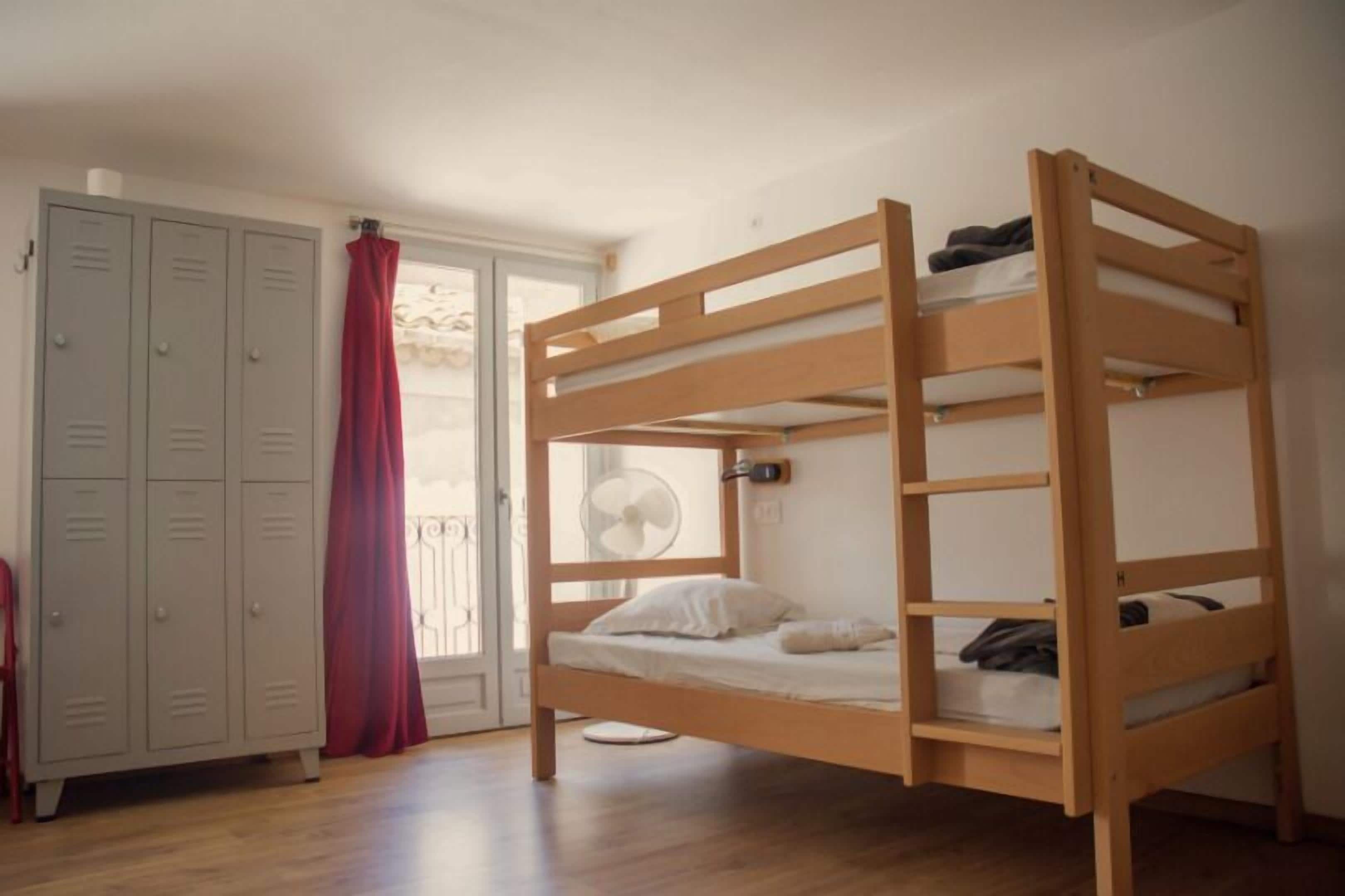 A bunk bed with a fan, a wardrobe, and a red curtain.