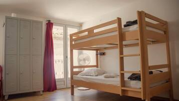 A bunk bed with a fan, a wardrobe, and a red curtain.