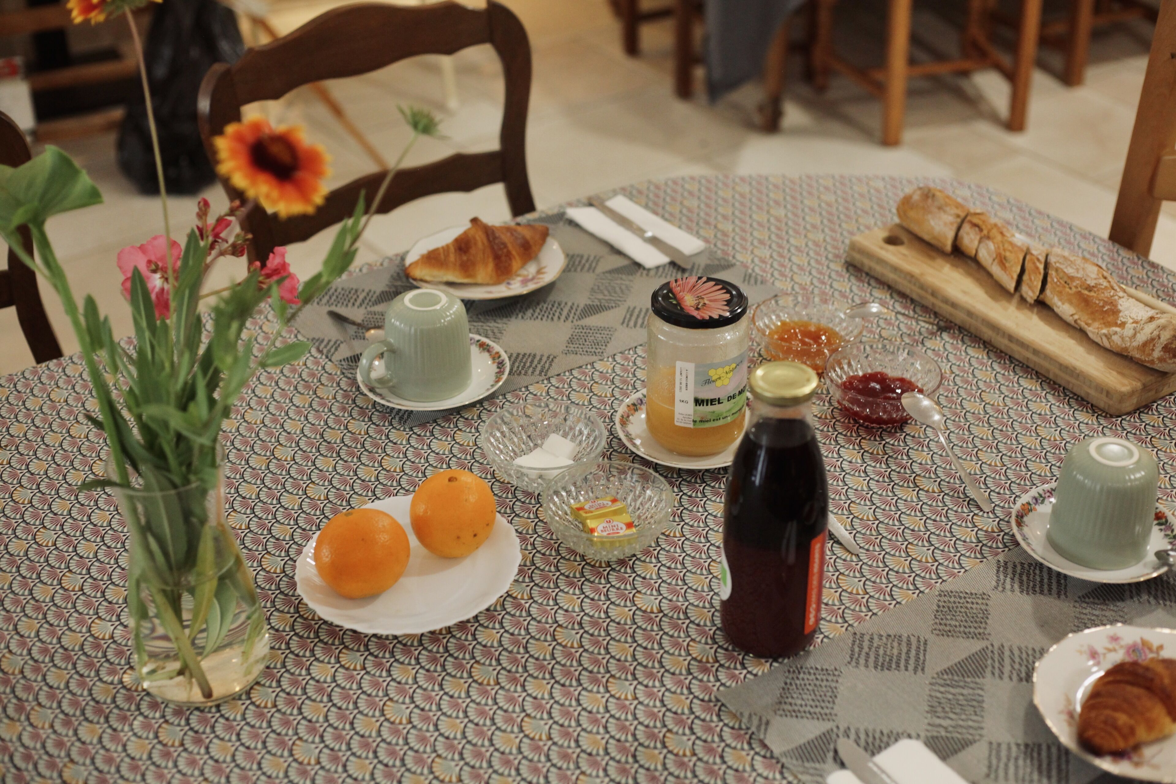 A dining table with plates, a bottle, and a vase with flowers.