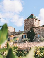Un edificio de piedra con una torre, techo de tejas y una ventana pequeña.