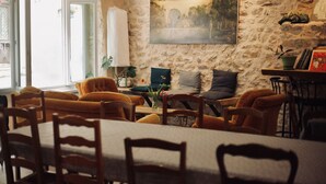 A dining area with a stone wall, a painting, and a table with chairs. - Hostel Le Diablotin (Saint-Jean-de-Fos)