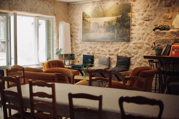Un coin repas avec un mur en pierre, un tableau et une table entourée de chaises.