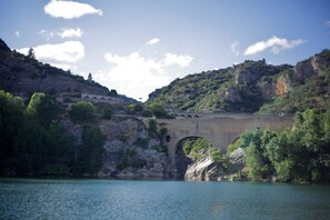 Un pont de pierre enjambant une rivière, avec une chaîne de montagnes en arrière-plan.