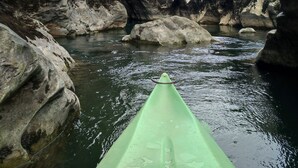 A kayak in a rocky river canyon with a building in the background. - Hostel Le Diablotin (Saint-Jean-de-Fos)