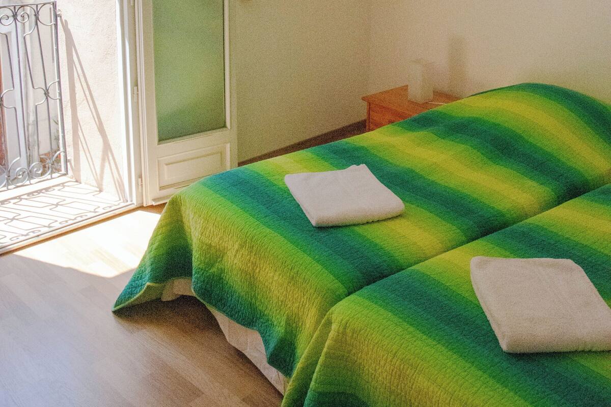 A room with a bed, a wooden shelf, and a door leading to an outdoor area.