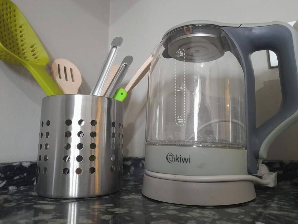 A kitchen with a kettle and a utensil holder.