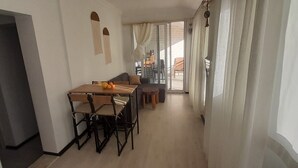 A dining area with a table and chairs, a sofa, and a view of the outdoors. - Oludeniz Evleri (Fethiye)