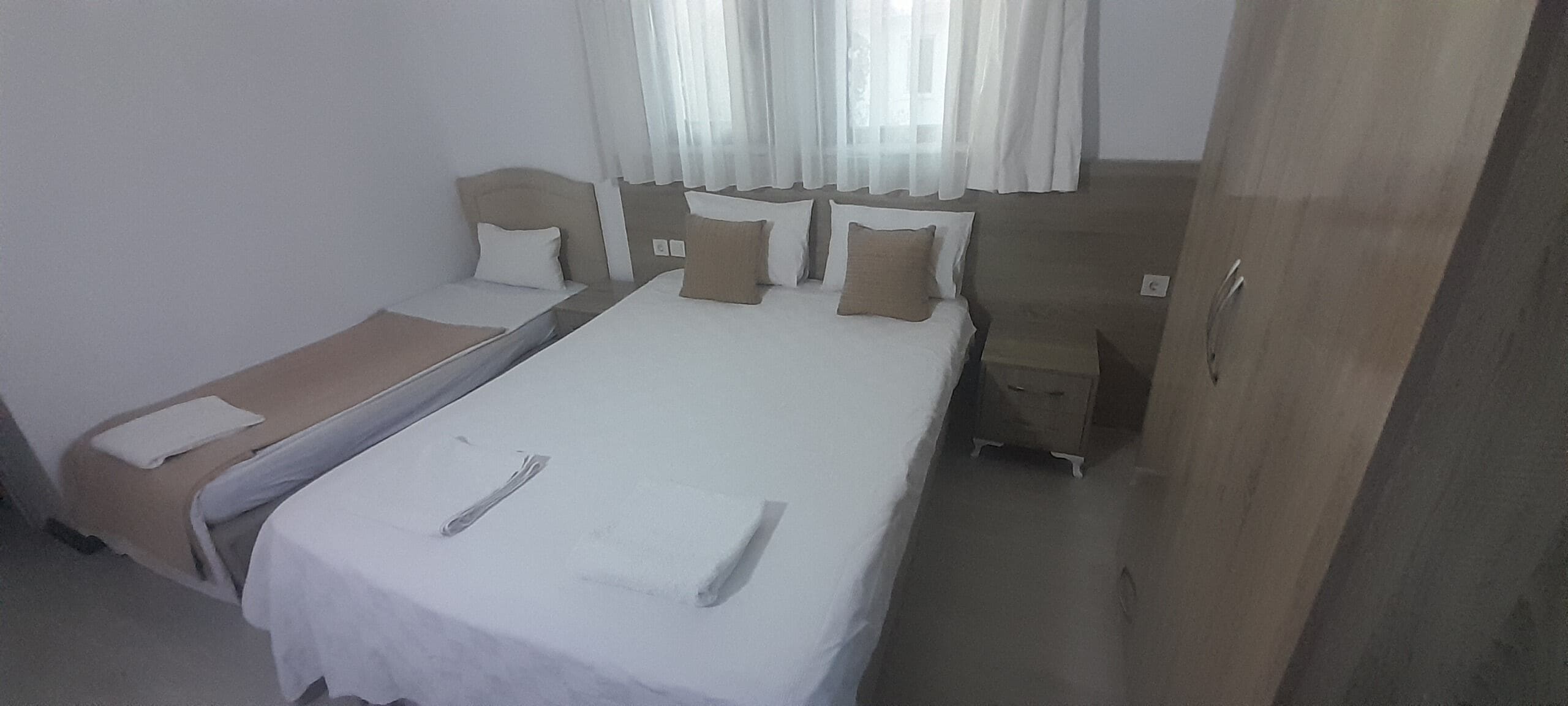 Une chambre avec un lit simple, un petit lit, une armoire et une table de chevet.