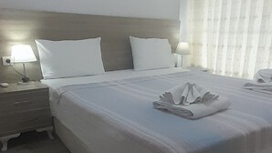 A hotel room with a large bed, a nightstand, a lamp, and an air conditioning unit. - Oludeniz Evleri (Fethiye)
