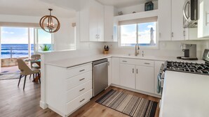 A modern kitchen with white cabinetry, a stainless steel dishwasher, and a gas stove.