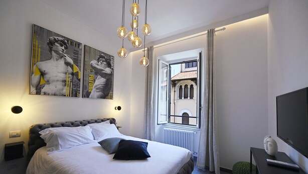 A modern hotel room with a large bed, a view of a building through an open window, and artwork on the wall. - Sistina36 Spanish Steps Apartment (Roma)