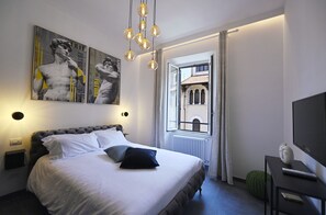 A modern hotel room with a large bed, a view of a building through an open window, and artwork on the wall. - Sistina36 Apartment near the Spanish Steps (Roma)