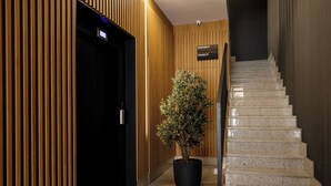 En moderne hotellobby med reception, en potteplante og en trappe.