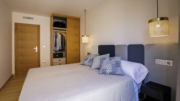 A bedroom with a bed, a wardrobe, a bedside table, and a hanging light fixture.