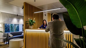 Et receptionsområde med en træreception, en sofa og en potteplante.