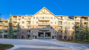 A multi-story hotel with a central entrance, balconies, and a stone facade.