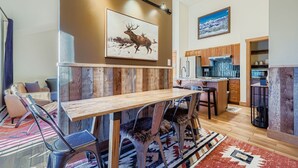A modern kitchen with wooden cabinets, a built-in oven, and a dining area with a wooden table and chairs.