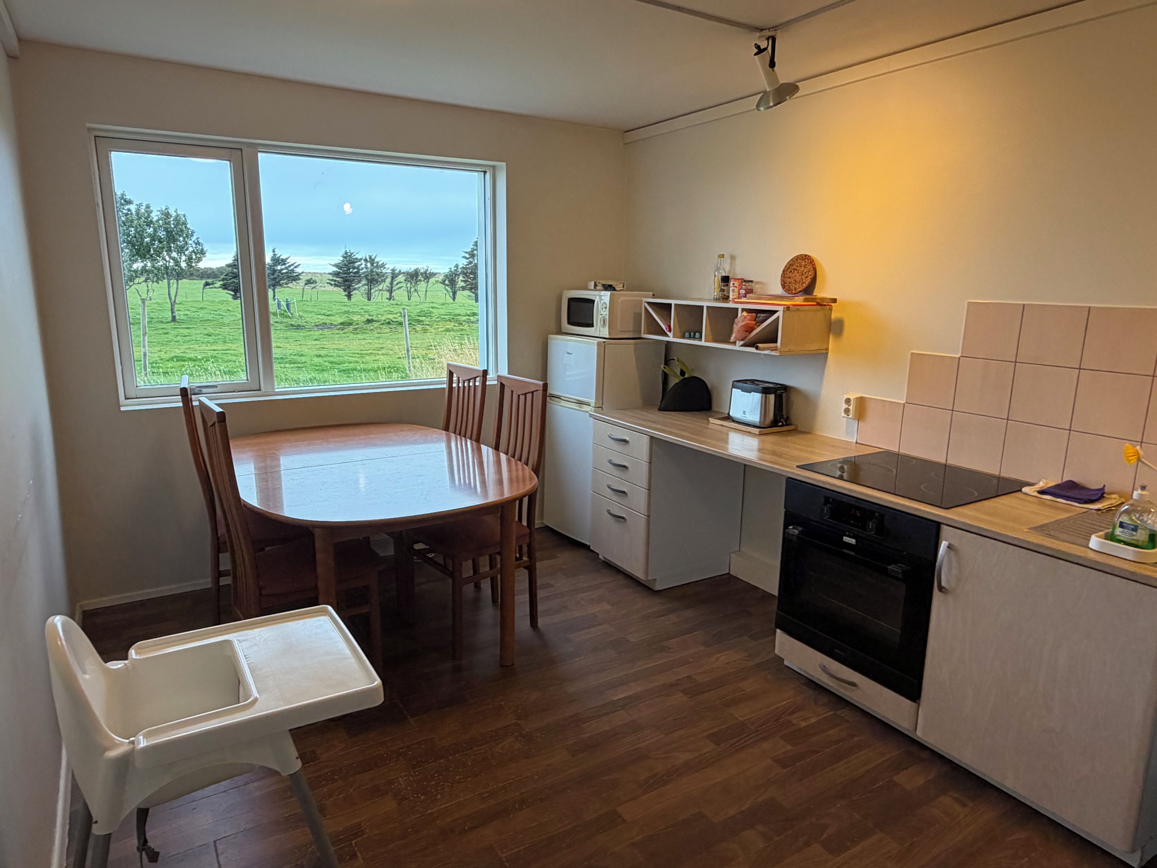 A compact kitchen with a dining table, chairs, a microwave, a toaster, and a dishwasher.