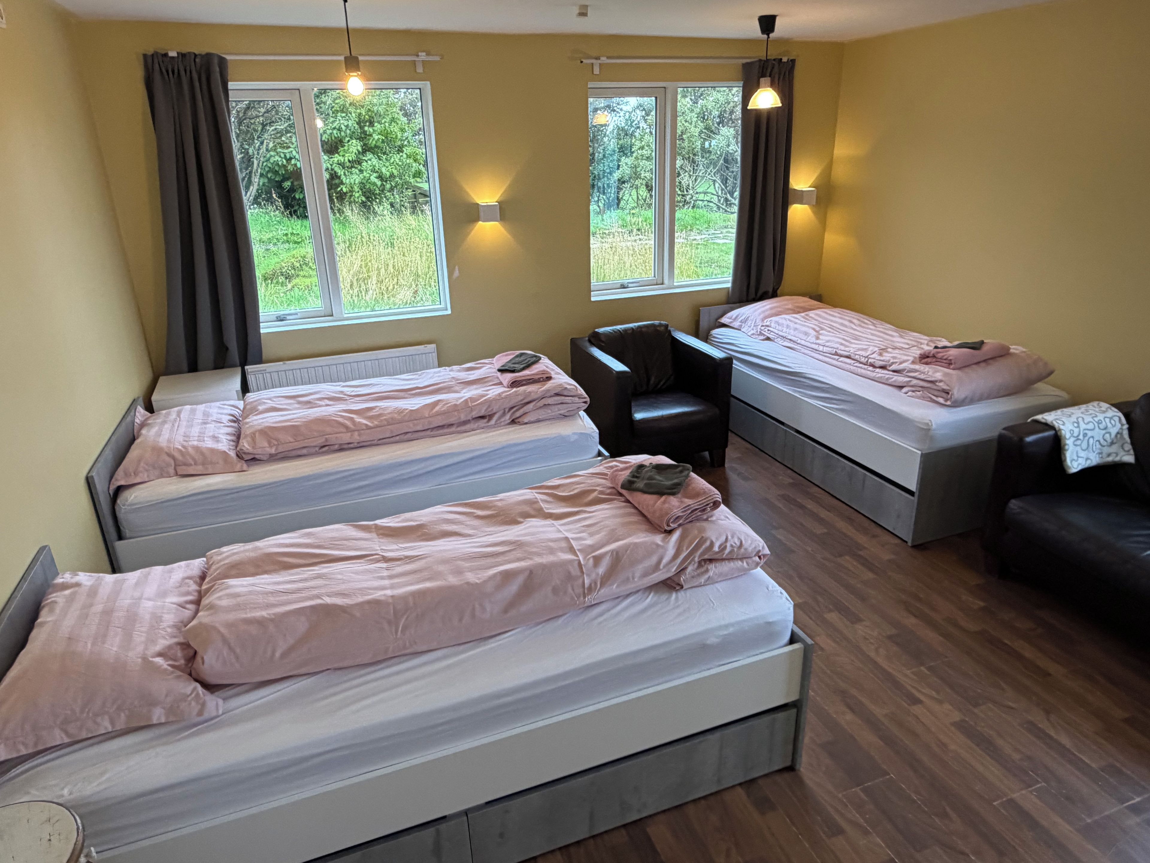 A room with three beds, a desk, and two chairs.