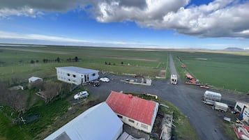 Une propriété rurale comprenant un grand bâtiment blanc, une grange à toit rouge et un chemin de gravier qui traverse de vastes champs.