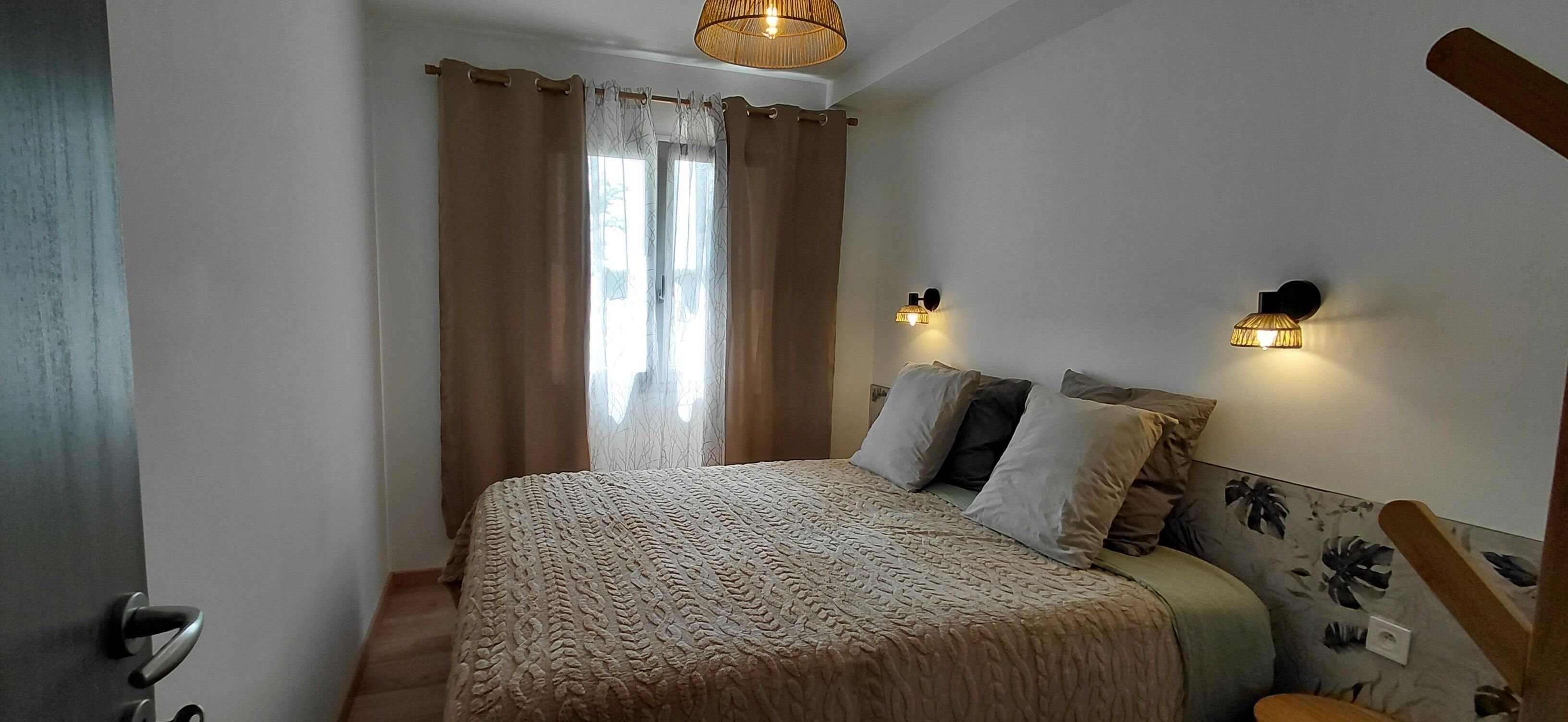 Ein Schlafzimmer mit einem Bett, Vorhängen, Wandleuchten und einer Wand mit Muster.