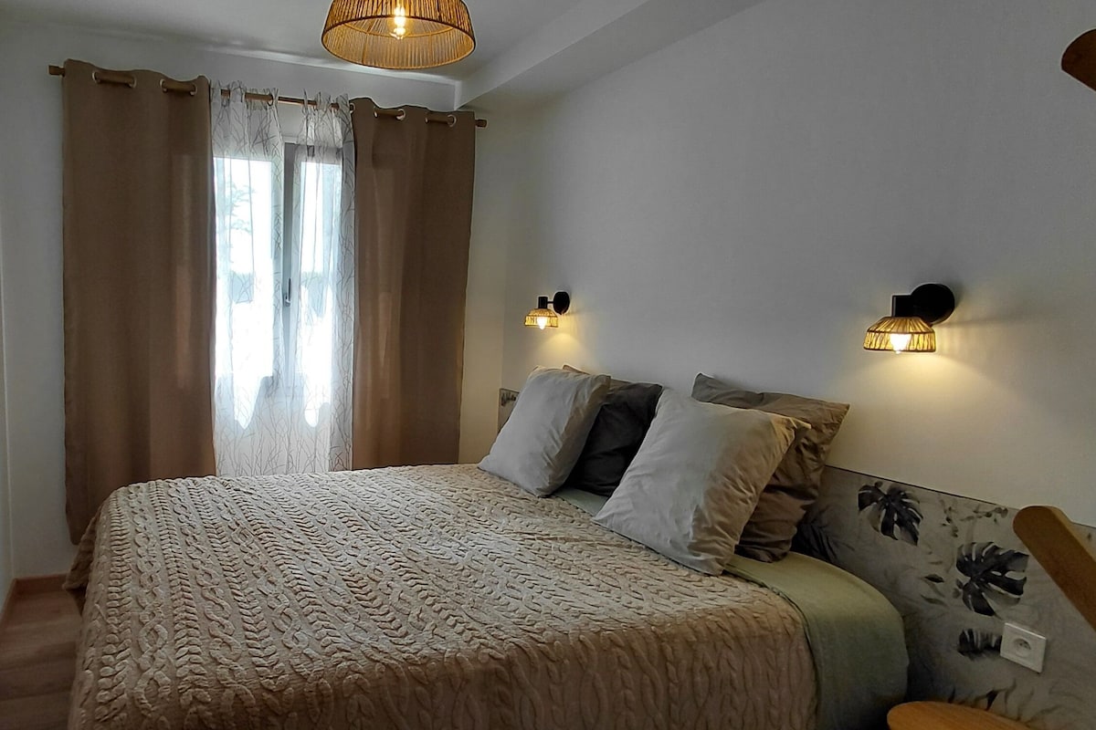 A bedroom with a bed, curtains, wall-mounted lights, and a patterned wall.
