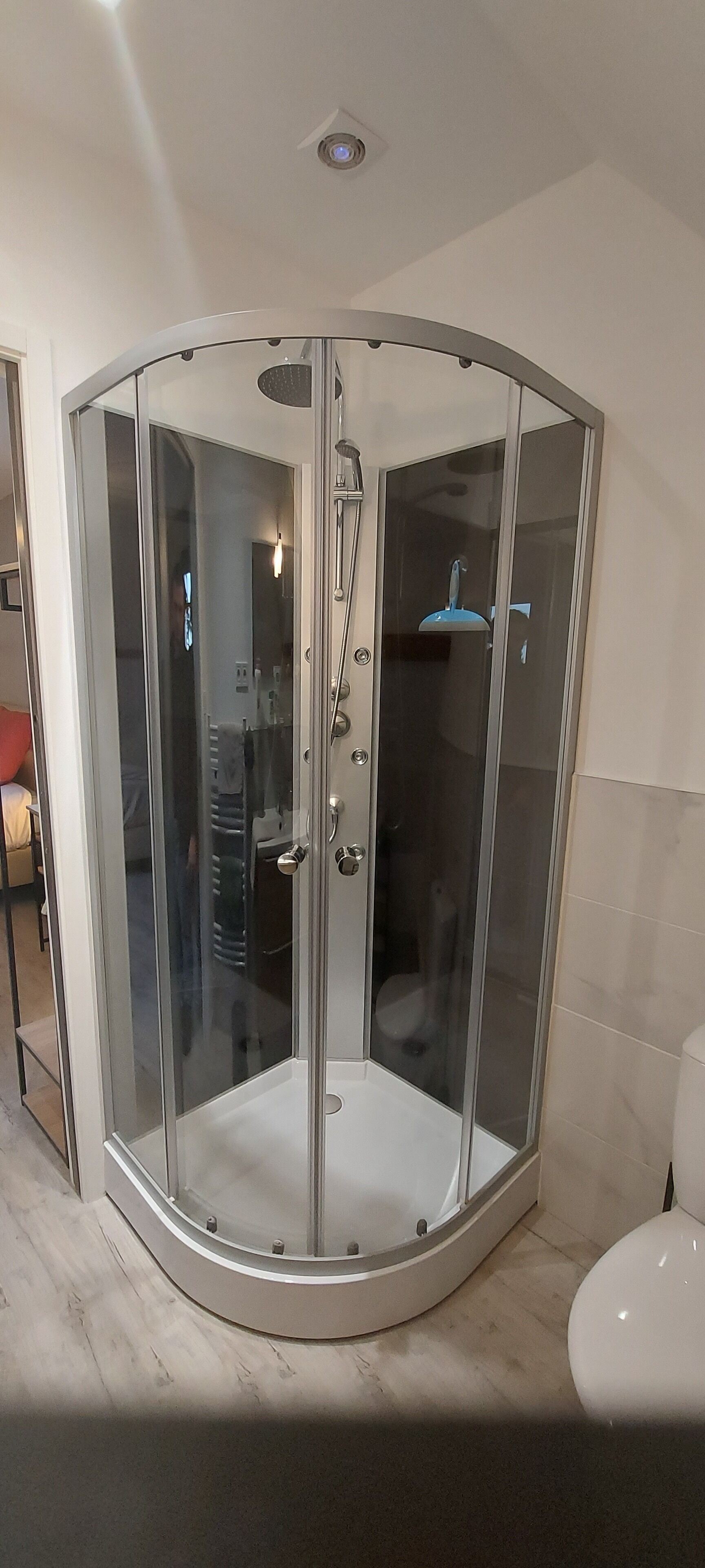 Un receveur de douche d’angle avec une porte en verre et un pommeau de douche.