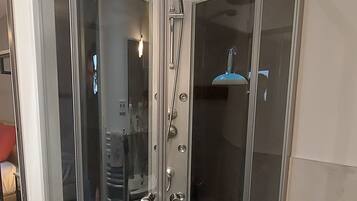 Un receveur de douche d’angle avec une porte en verre et un pommeau de douche.