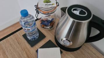 Ein Edelstahlkessel, eine Wasserflasche, ein Glasbehälter mit Etikett und ein Blatt Papier auf einer Holztischplatte.