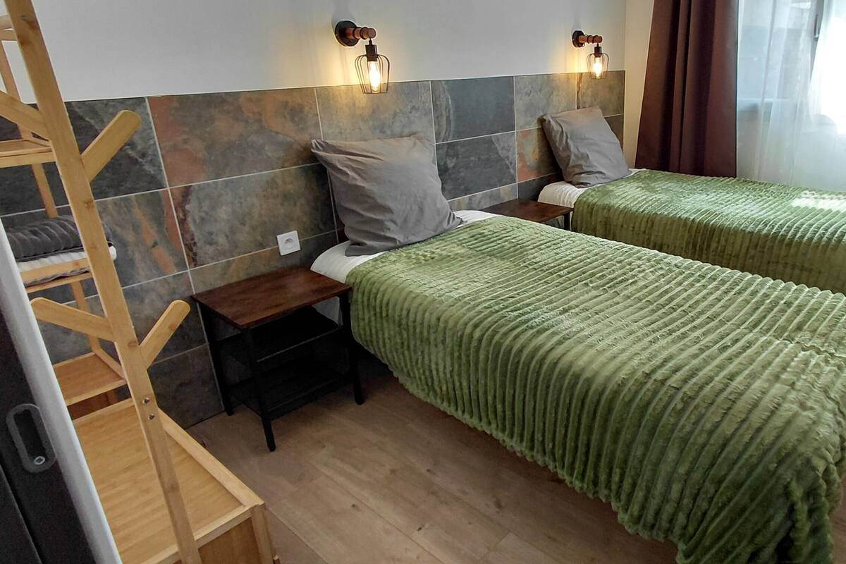 Une chambre avec deux lits, deux tables de chevet en bois, une chaise en bois et une petite table.