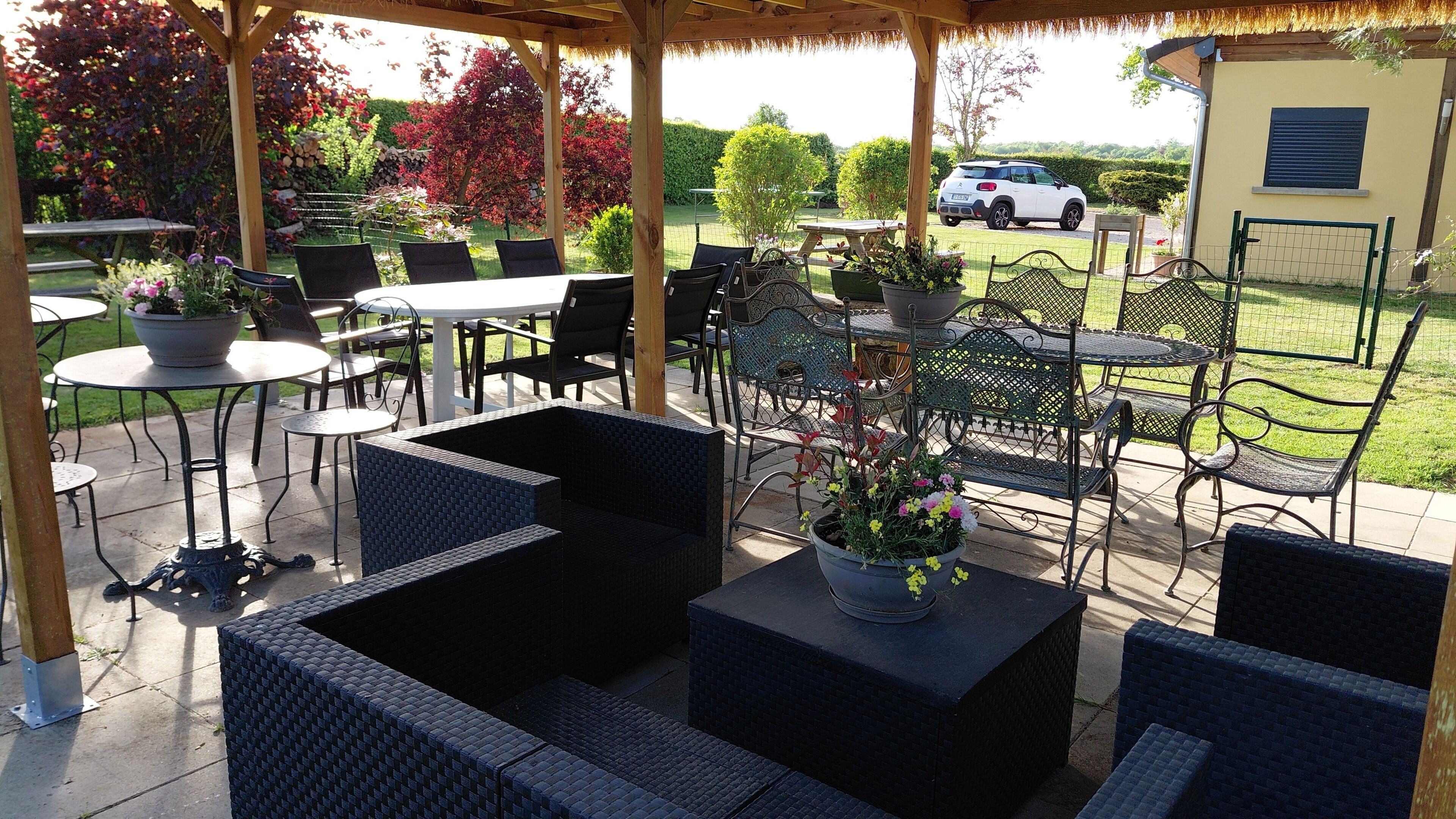Une terrasse extérieure avec des meubles en osier, une table et des chaises.