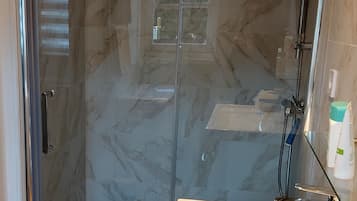 Une salle de bain avec une douche à parois de verre, un lavabo blanc et un miroir.