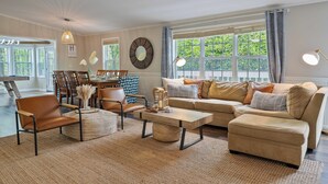 A spacious living room with a large window, a dining area with a wooden table, and a cozy seating arrangement. - New Game Room-Snow Cones-Pet Friendly-Dock-Fire Pit-Kayaks-Paddleboards- (Martin)
