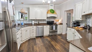 A modern kitchen with white cabinetry, stainless steel appliances, and a central island. - New Game Room-Snow Cones-Pet Friendly-Dock-Fire Pit-Kayaks-Paddleboards- (Martin)