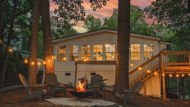 A cozy outdoor seating area with Adirondack chairs, a fire pit, and string lights. - New Game Room-Snow Cones-Pet Friendly-Dock-Fire Pit-Kayaks-Paddleboards- (Martin)